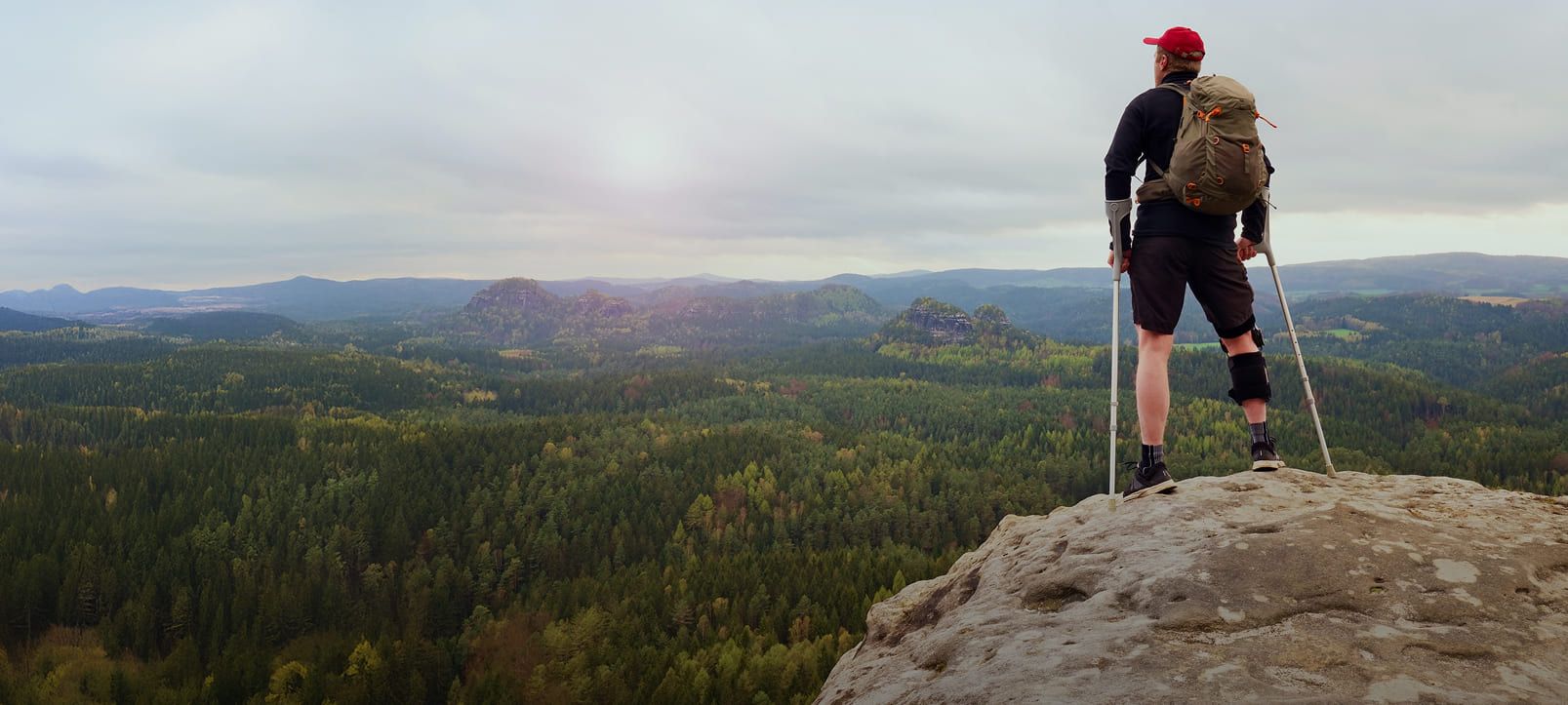 Mann mit Gehhilfe auf einem Berg